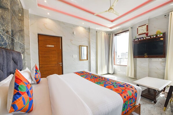 A hotel room with a bed, a desk, a TV, and a view of the city. - Fabhotel Paradise (Kharar)