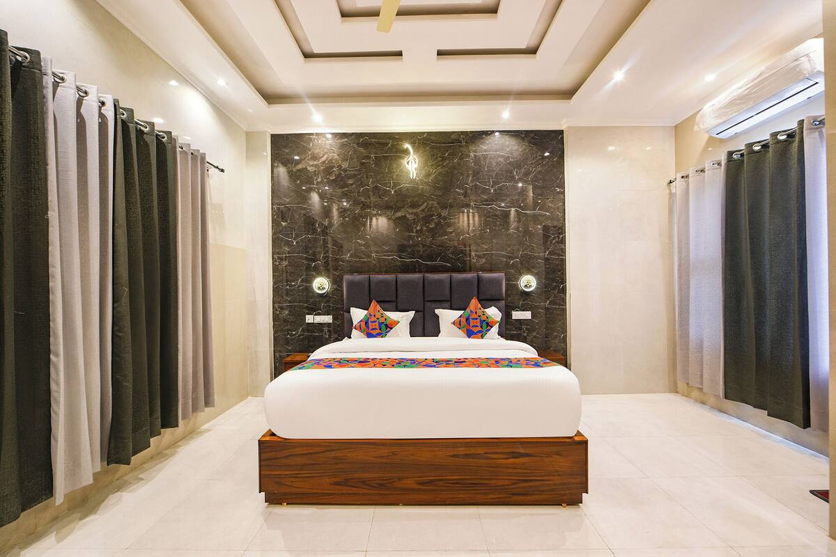 A modern bedroom with a large bed, marble wall, and curtains.