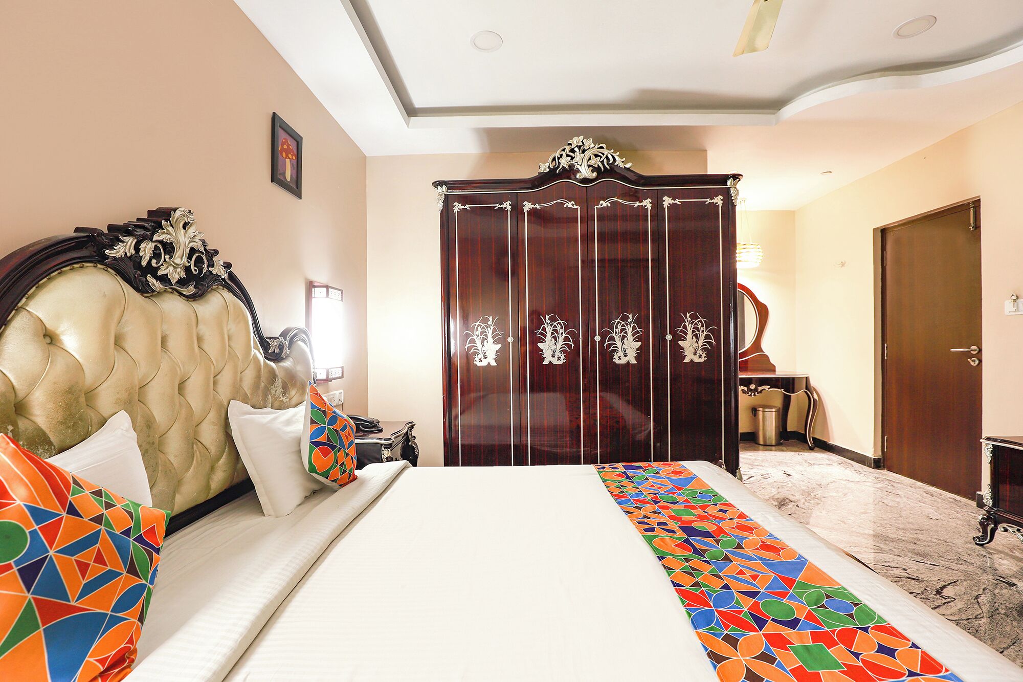 A hotel room with a large bed, a wardrobe, and a small table with a lamp.