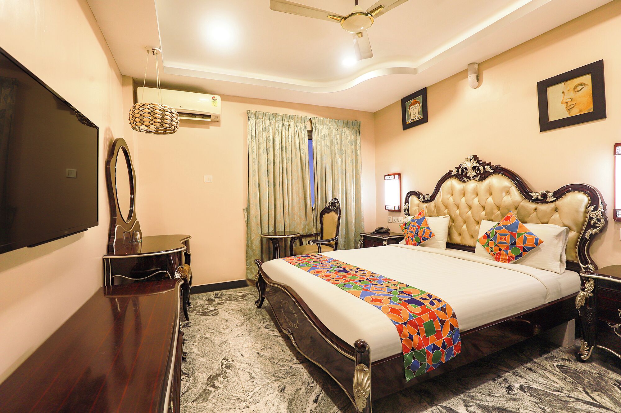 A hotel room with a large bed, a flat-screen TV, an air conditioning unit, a ceiling fan, a desk, and a chair.