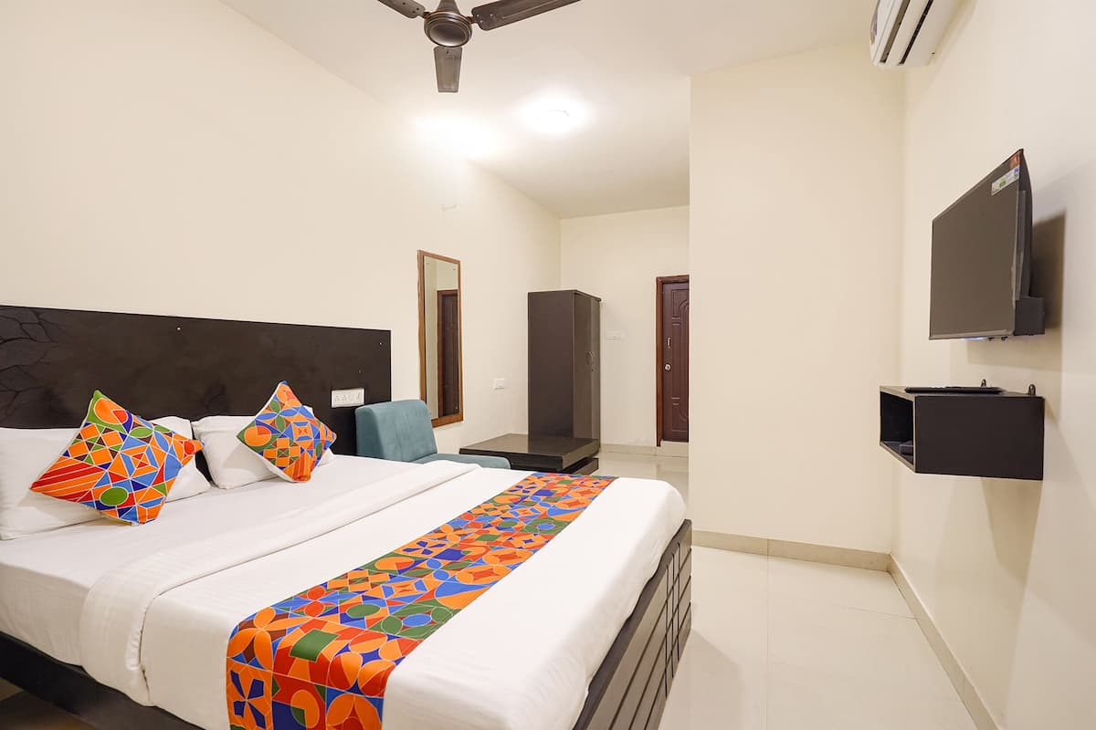 A hotel room with a bed, pillows, a TV, and a wardrobe.