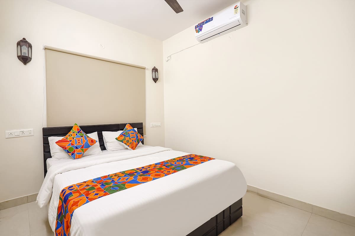 A neatly made bed with a colorful bedspread, a headboard, and two wall-mounted lamps.