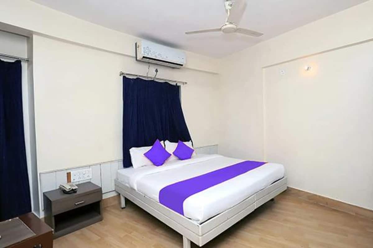 Une chambre d’hôtel comprenant un lit, une table de chevet, une armoire et un ventilateur de plafond.