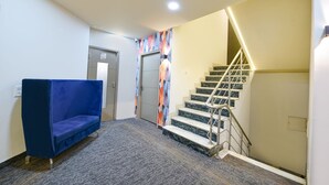 A hotel lobby with a blue sofa, a staircase, and a colorful wall. - Fabhotel Vintage Inn (New Delhi)