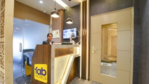 A reception desk with a 'fab hotels' sign, a television, and a wooden panel design. - Fabhotel Vintage Inn (New Delhi)