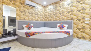 Un dormitorio moderno con una cama curvada, un cabecero tapizado en gris y papel tapiz estampado.