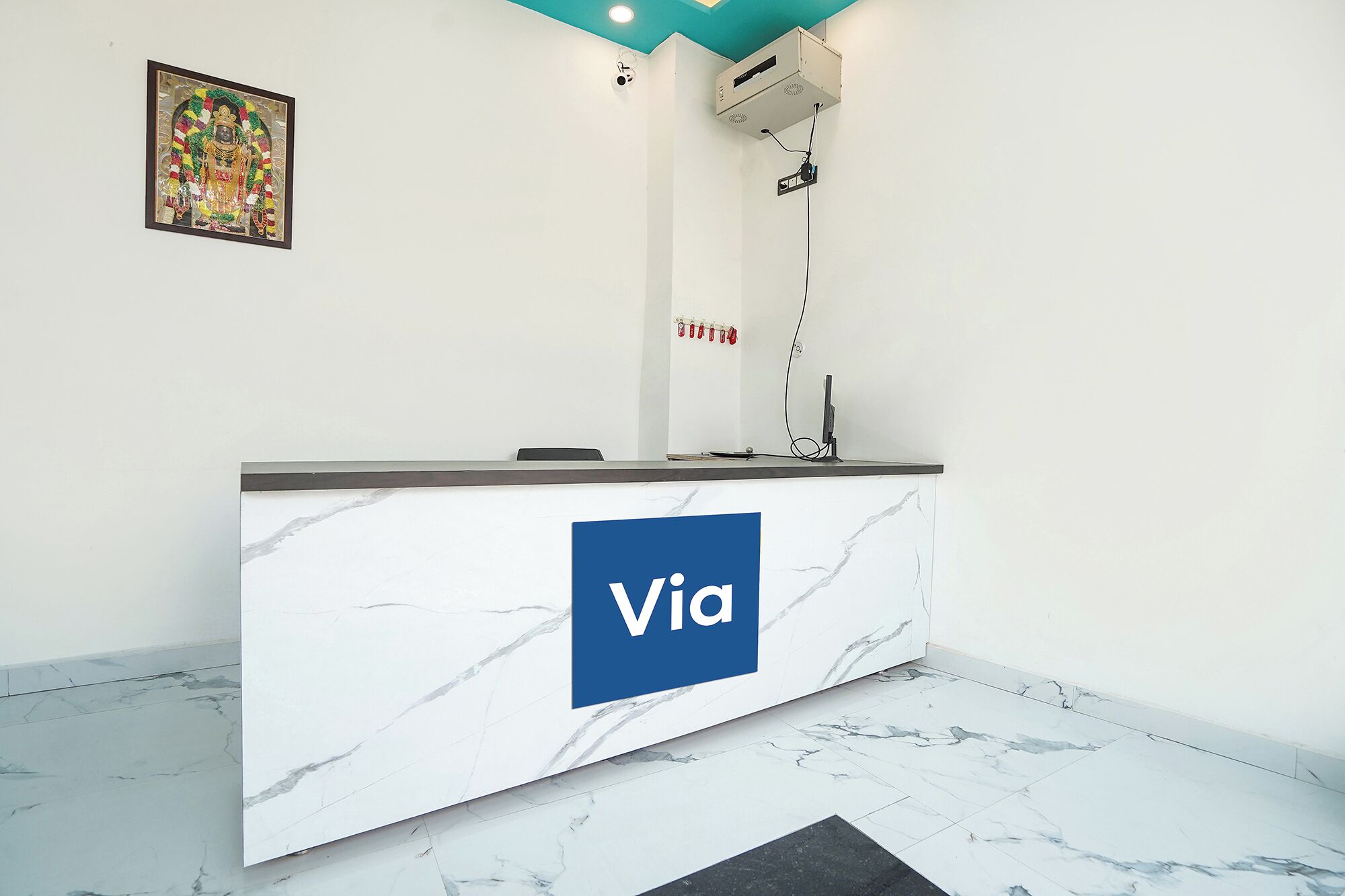 A reception desk with a marble top and a blue logo, air conditioning unit, and a security camera on the wall.
