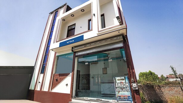 A building with a 'Via' sign, a glass entrance, and a sign for the 'Awdah Royal Hotel' advertising a wedding venue. - FabExpress Awadh Royal (Faizabad)