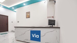 A reception desk with a marble top and a blue sign that reads 'Via.' - FabExpress Awadh Royal (Faizabad)