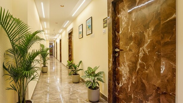 A hotel corridor with marble flooring, potted plants, and framed artwork on the walls. - FabHotel Millenium (Mumbai)