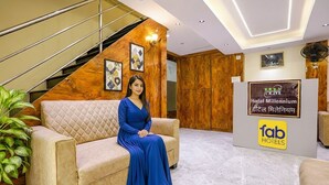 A hotel lobby with a staircase, a reception desk, and a person seated on a sofa. - FabHotel Millenium (Mumbai)