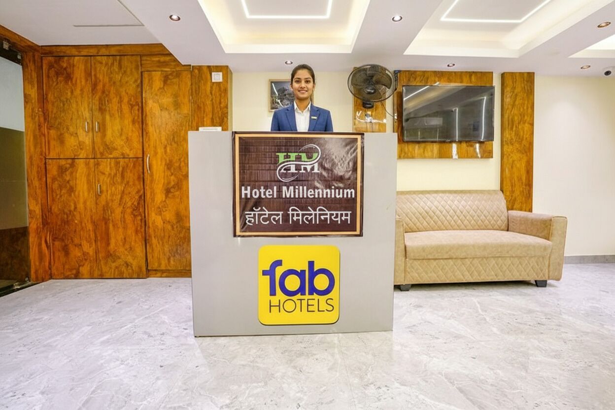 A hotel reception area with a wooden cabinet, a beige sofa, and a fan.