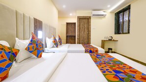 A hotel room with two beds, each with colorful geometric-patterned pillows, a large window, and an air conditioning unit on the wall. - FabHotel Millenium (Mumbai)