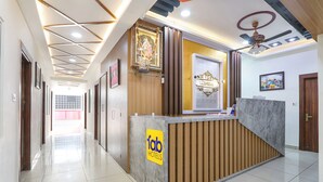 A hotel reception area with a wooden reception desk, a sign reading "fab hotels," and a ceiling with recessed lighting and a decorative fan. - Fabhotel Vgr Comforts (Hyderabad)