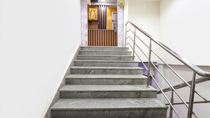 A staircase with metal railings leading to a room with a wooden door and a framed picture on the wall. - Fabhotel Vgr Comforts (Hyderabad)