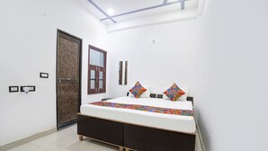 A bedroom with a bed, a wardrobe, a door, and a mirror. - Fabhotel Om Palace (Faizabad)