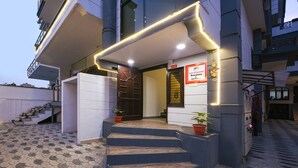 A hotel entrance with a set of stairs leading up to the door, a reception desk, and a sign indicating the hotel name and reception location. - Fabhotel Silver Stone (Noida)