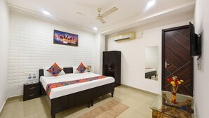 A bedroom with a bed, a nightstand, a dresser, a mirror, and a ceiling fan. - Fabhotel Silver Stone (Noida)