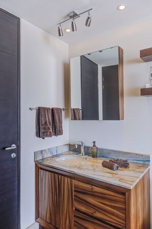 A bathroom with a marble sink, wooden vanity, a large mirror, and a towel rack.
