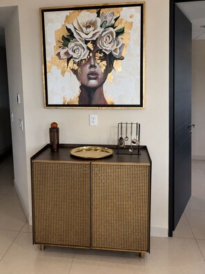 A modern interior with a framed artwork above a console table, a door to the right, and a wall socket below.
