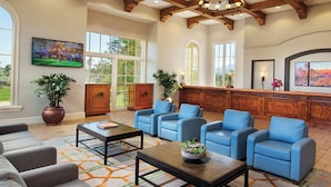 A spacious lobby with a large seating area, a wooden reception desk, and a large window offering a view of the outdoors. - Coachella Fun and Luxury in the Desert - Marriott Shadow Ridge II - The Enclaves (Palm Desert)