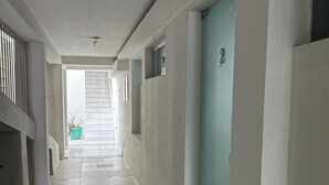 Un couloir aux murs blancs, une porte bleue et un sol carrelé.