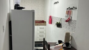 Une cuisine compacte comprenant un réfrigérateur, une table à manger avec des chaises et un petit plan de travail avec une machine à café.