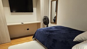 Een moderne slaapkamer met een groot bed, een aan de muur bevestigde televisie en een houten vloer.
