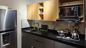 Een moderne keuken met zwarte kastjes, een roestvrijstalen koelkast, een magnetron en een koffieapparaat.