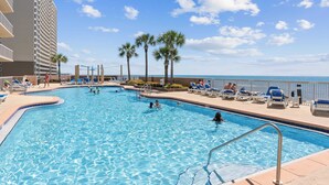 A swimming pool with lounge chairs and palm trees, surrounded by a hotel building. - Oceanfront Condo w/ Pool + Pier Park Access Front Beach Retreat by Avantstay (Panama City Beach)