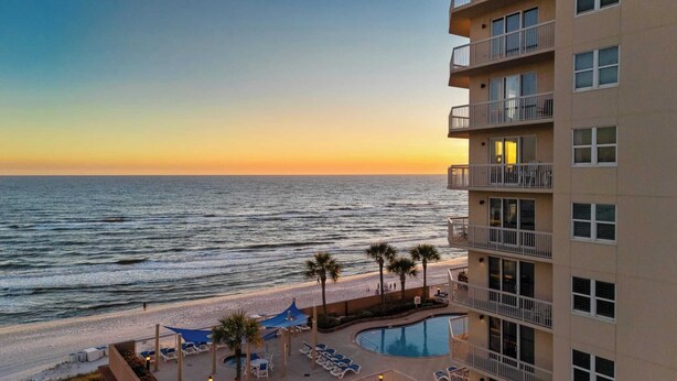 A beachfront hotel with a swimming pool, beach chairs, and palm trees. - Oceanfront Condo w/ Pool + Pier Park Access Front Beach Retreat by Avantstay (Panama City Beach)
