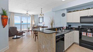 A modern kitchen with a central island, white cabinets, and a black stove. - Oceanfront Condo w/ Pool + Pier Park Access Front Beach Retreat by Avantstay (Panama City Beach)