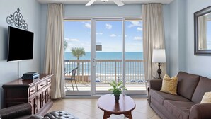 A living room with a television, a sofa, a coffee table, and a balcony with a view of the beach. - Oceanfront Condo w/ Pool + Pier Park Access Front Beach Retreat by Avantstay (Panama City Beach)