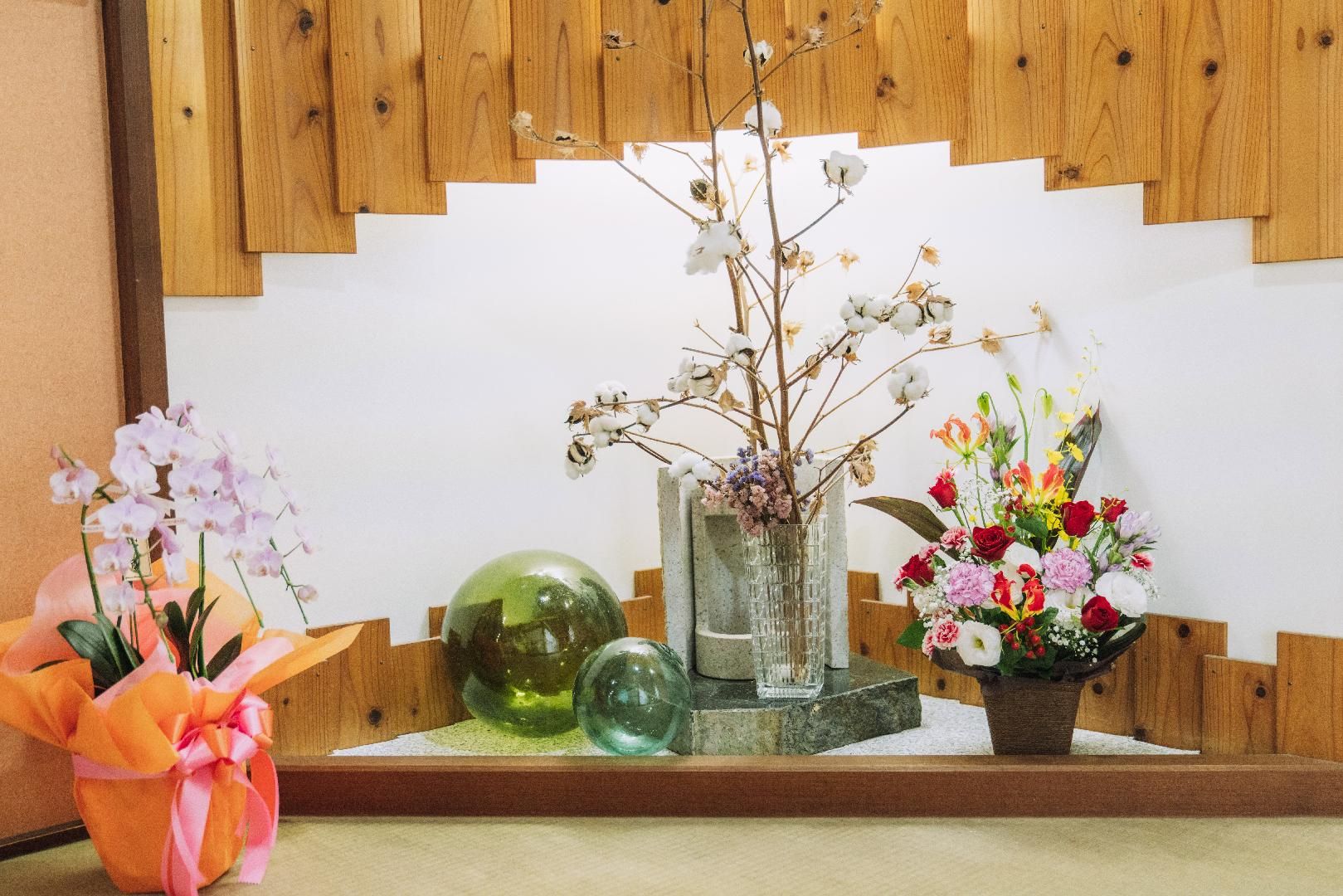 A wooden bench with a vase of flowers and a glass sculpture.