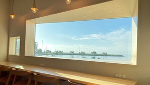 Una habitación con un ventanal grande que da a una masa de agua, una mesa de madera y varias sillas.