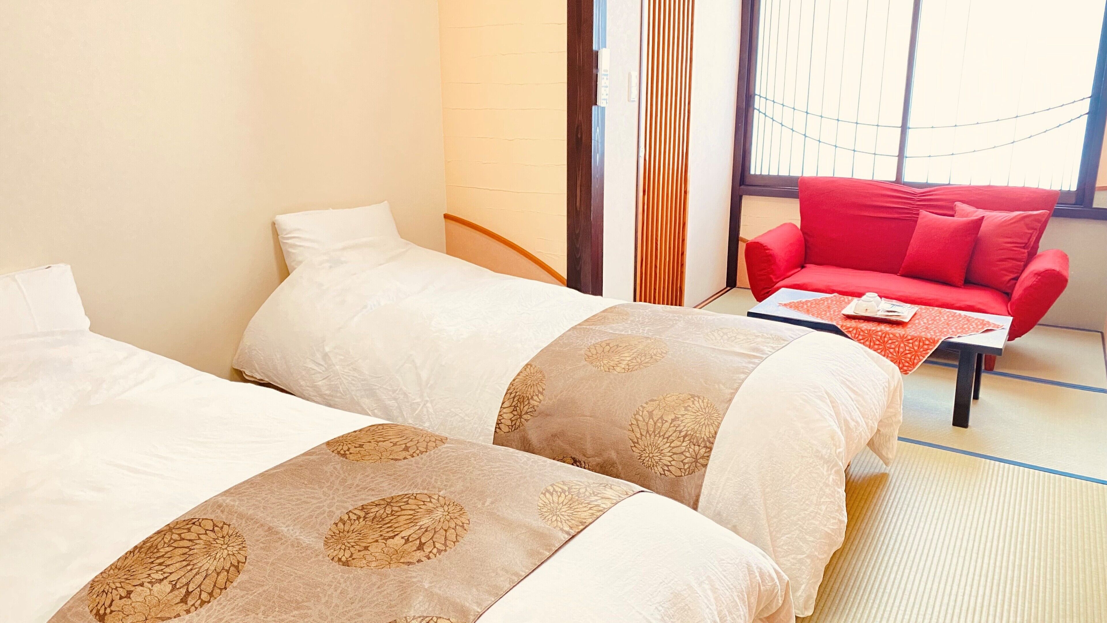 Una habitación de hotel con dos camas, un sofá rojo y una mesita con una bandeja.