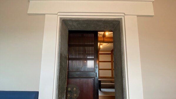 A doorway leading to a room with a dark wooden door and a metal grille. - Wafu Onsen Motoyu Kano (Himi)