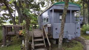 A rustic cabin with a wooden deck and a ladder leading to a window. - Kuju Aid Station (Kokonoe)