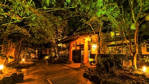 A traditional Japanese garden at night with a wooden structure, stone lanterns, and a stone pathway. - Higo Kaido Minamiaso Onsen Iyashi no Sato (Minamiaso)
