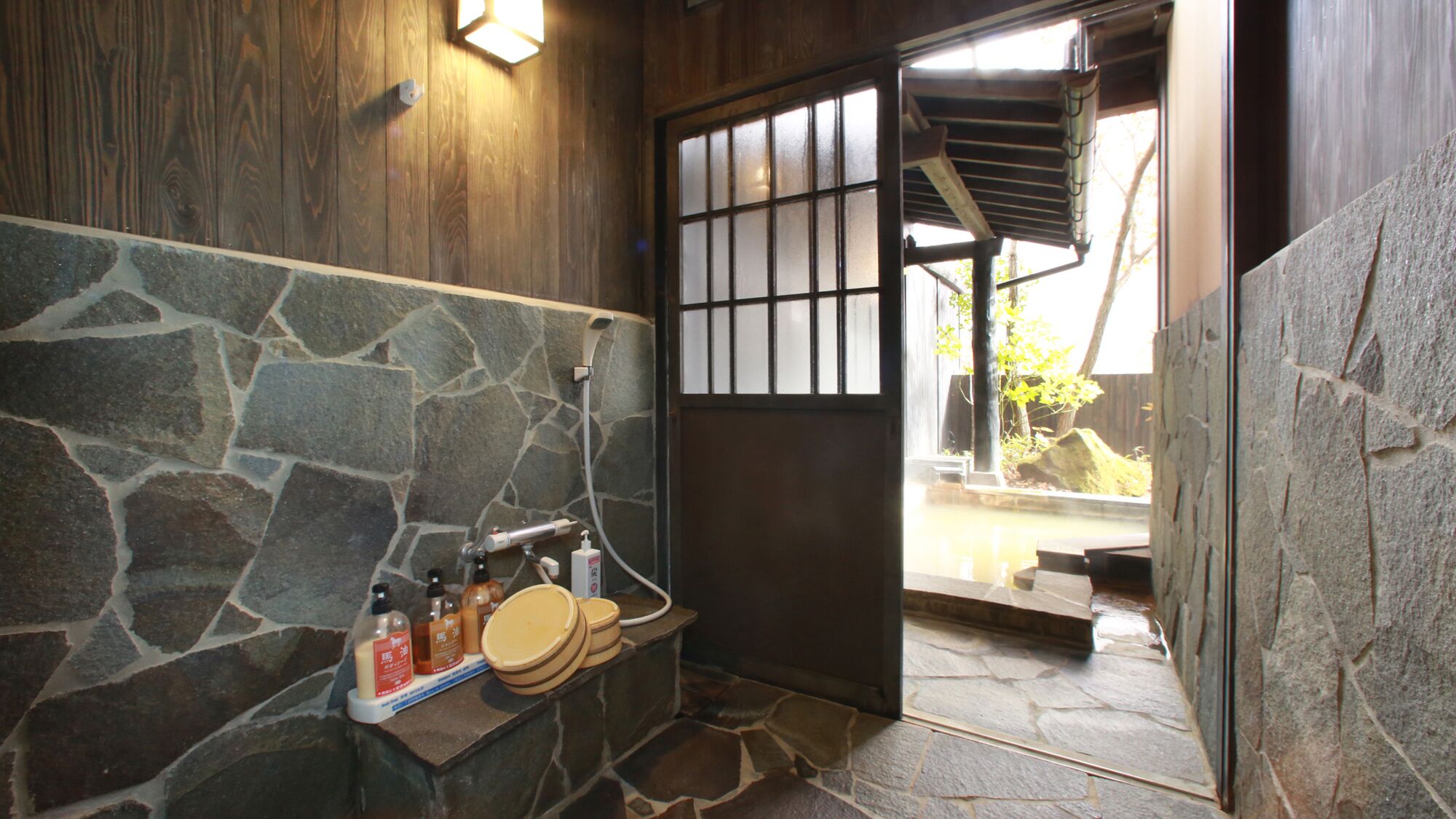 A stone wall, a wooden door, and a stone bench with toiletries.