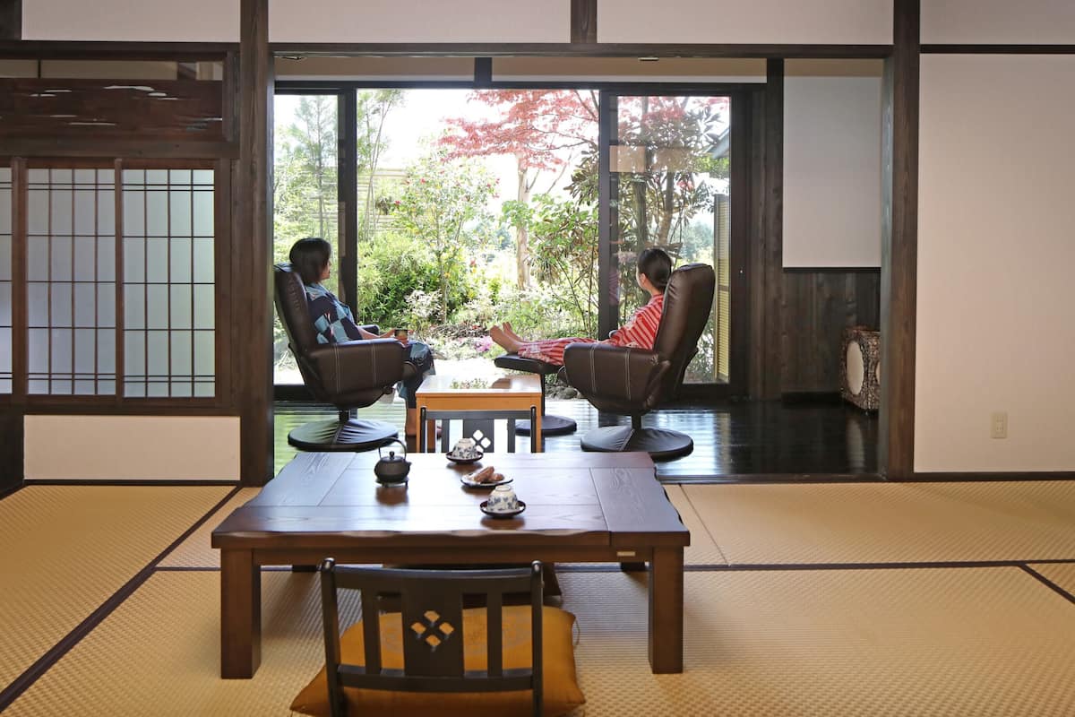 Ein traditioneller japanischer Raum mit Tatami-Boden, einem niedrigen Tisch und zwei Stühlen.