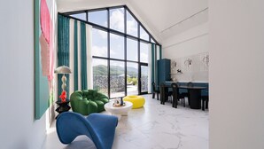 A modern living room with a large window, a dining area, and a view of mountains.