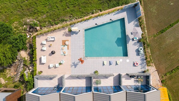 An aerial view of a resort with a large swimming pool, sun loungers, and a covered outdoor seating area. - Le Pavilion Pool Villa (Pohang)