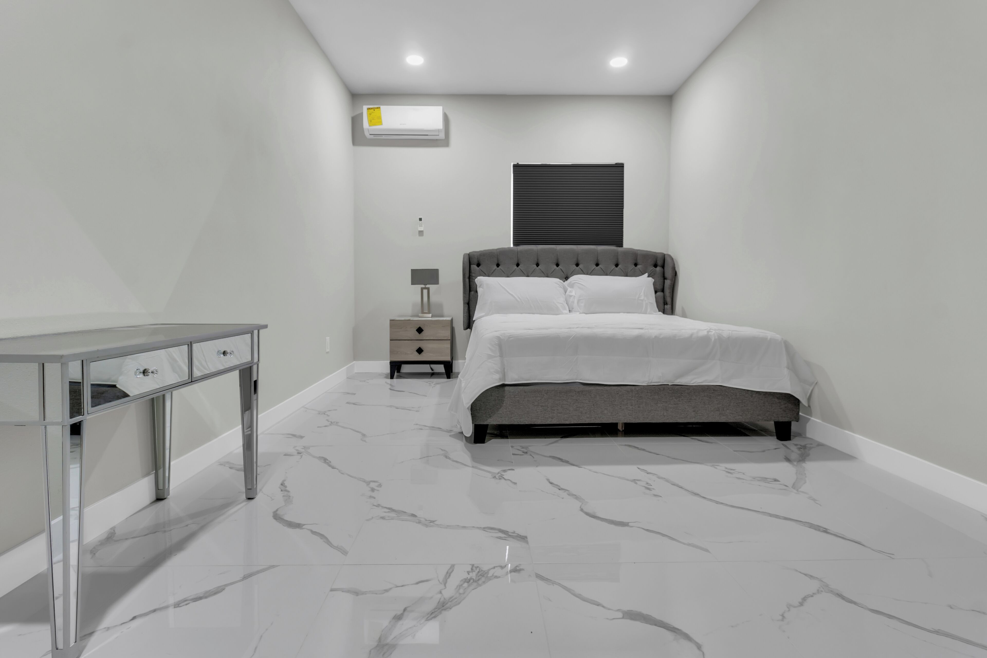 Une chambre à coucher comprenant un lit, une table de chevet, une commode et un appareil de climatisation.