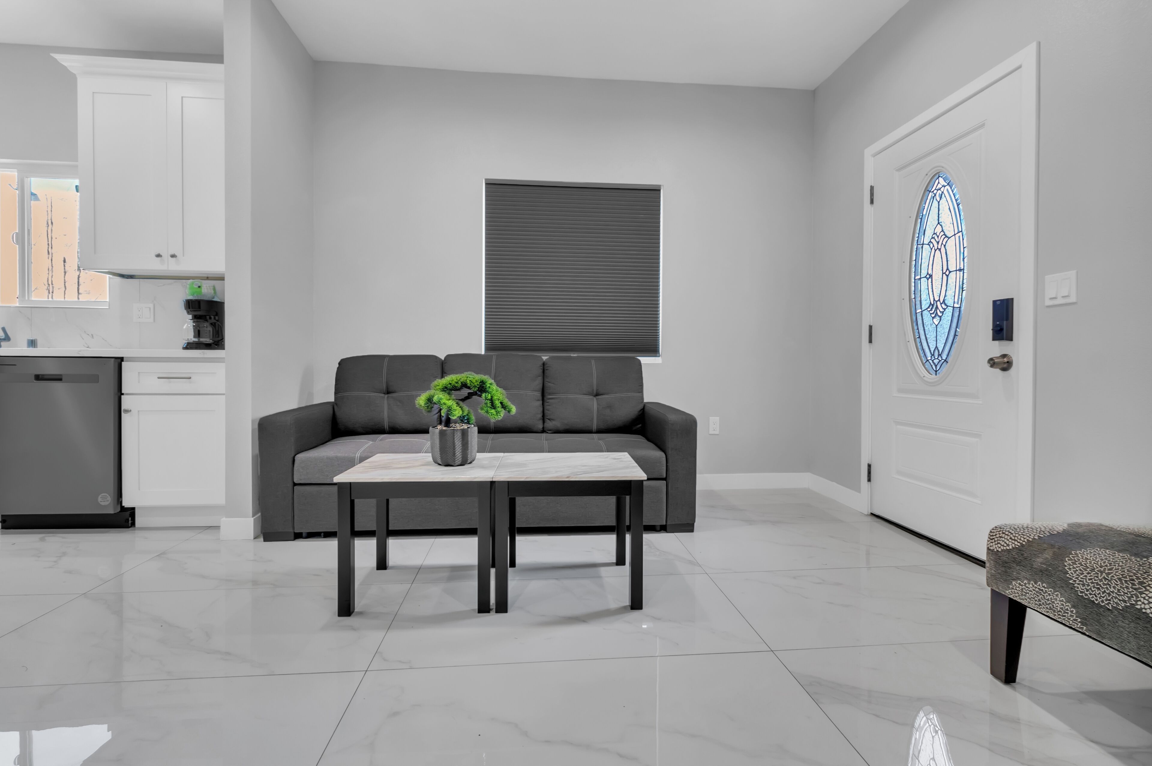 A modern living room with a grey sofa, a coffee table, and a potted plant.