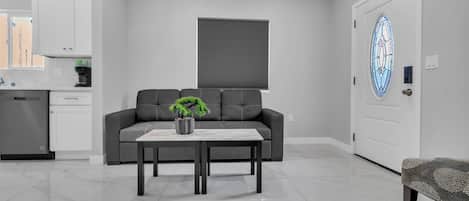 A modern living room with a grey sofa, a coffee table, and a potted plant.