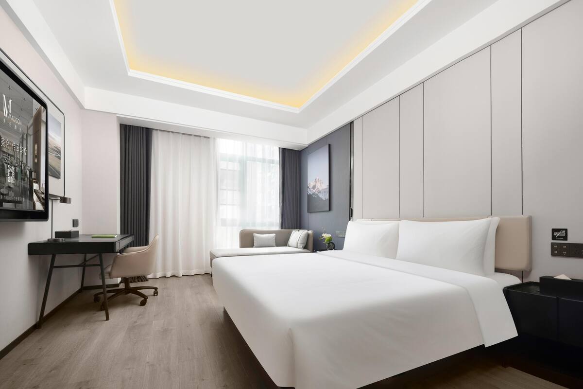 A modern hotel room with a large bed, a desk, and a chair.