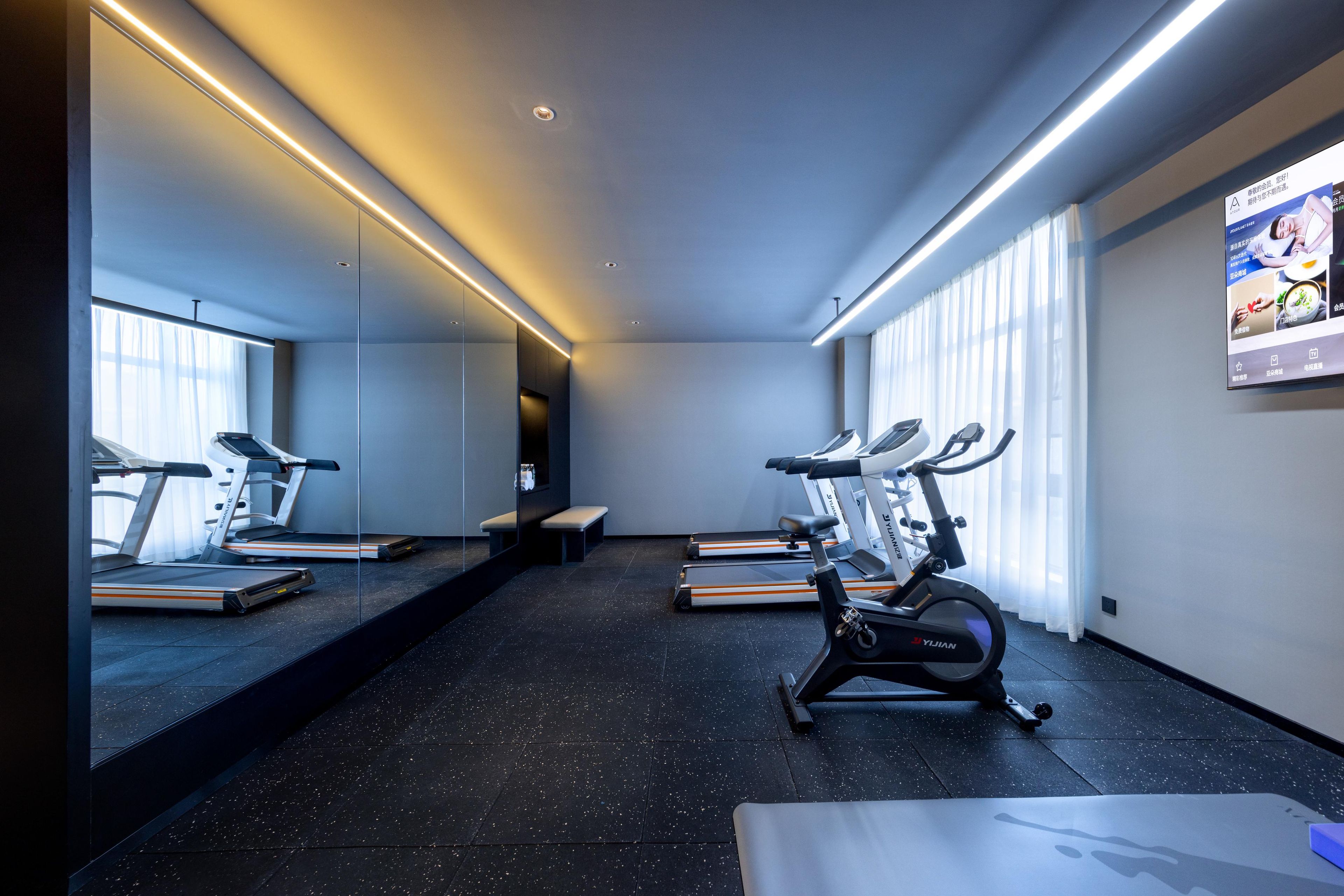 A modern gym with treadmills, an elliptical, and a bench.