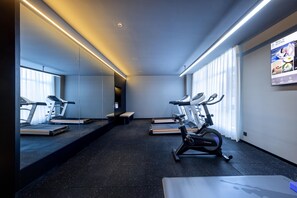 Et moderne fitnesscenter med løbebånd, crosstrainer og bænk.
