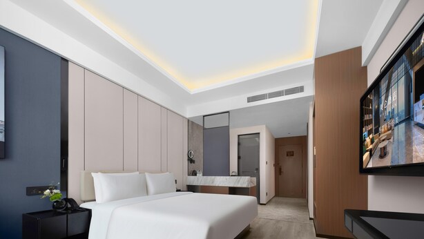 A modern hotel room with a large bed, a bedside table, a TV, and a wardrobe. - Meilun Hotel Xian Qujiang Convention Center Mixc (Xi'an)